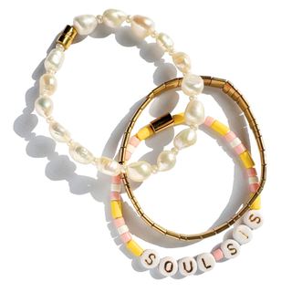 Three stacked beaded bracelets on a white background. The top bracelet features irregular white pearls with gold spacer beads.