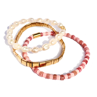 Three beaded bracelets arranged in a stack on a white background: one with white pearl-like beads, one with gold-toned segmented beads, and one with pink and coral beads.