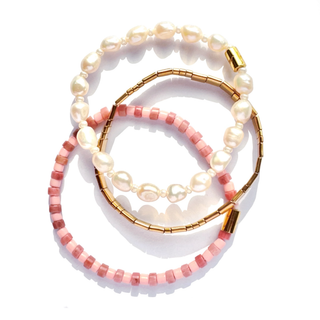 Three beaded bracelets arranged in a stacked circle on a white background: one with white freshwater pearls, one with pink faceted beads, and one with gold-toned metal beads and gold clasp.