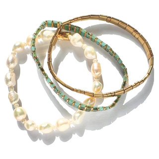 Three delicate bracelets arranged in a circle on a white background: one strand with irregular cream baroque pearls, one with small turquoise and gold beads, and one with a gold segmented bangle.
